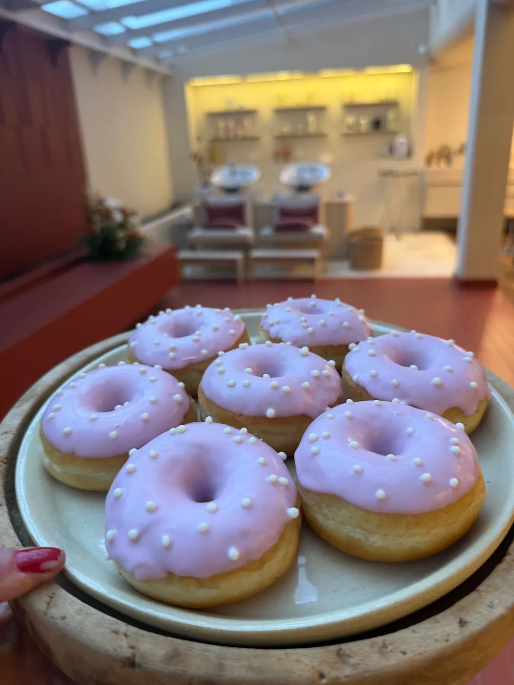 Prato de donuts rosa em primeiro plano, com o studio ao fundo
