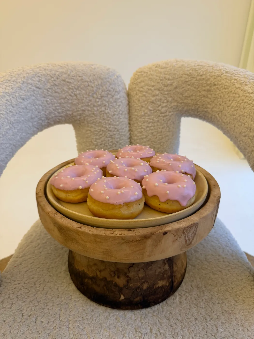 Donuts rosa na bandeja de madeira, sobre a poltrona de bouclê