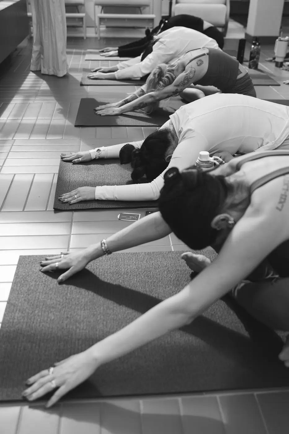 Fila de mulheres alongando no tapete de yoga (preto e branco)